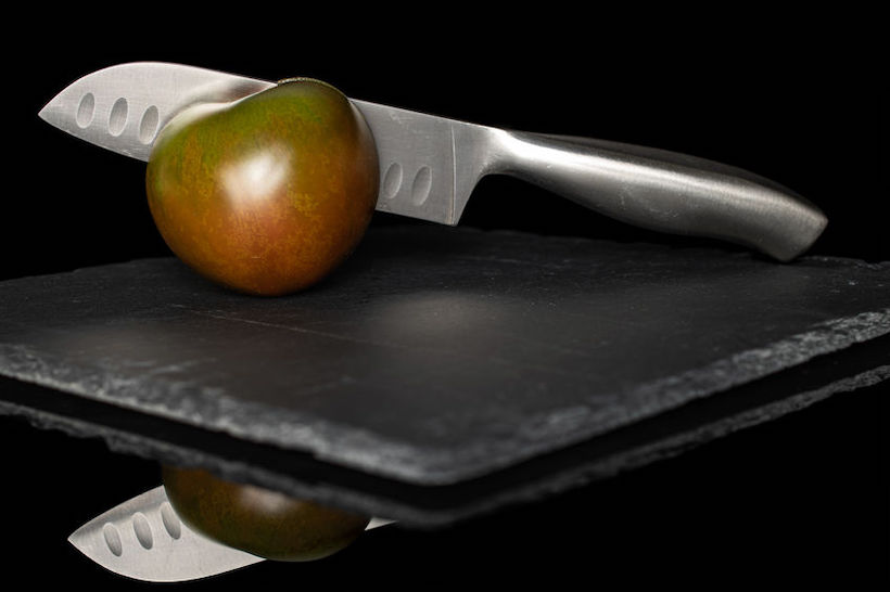 Fresh green red tomato isolated on black glass