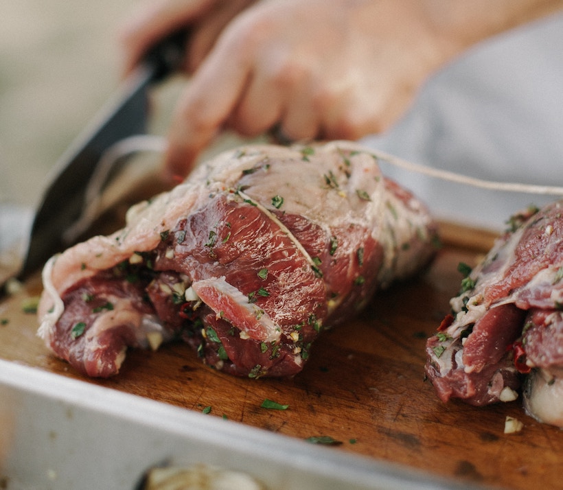 A man cuts meat with a butcher's knife