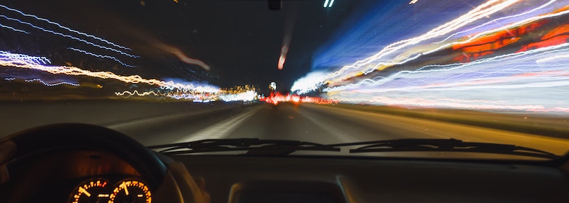 Car driving fast with blurry lights through windshield