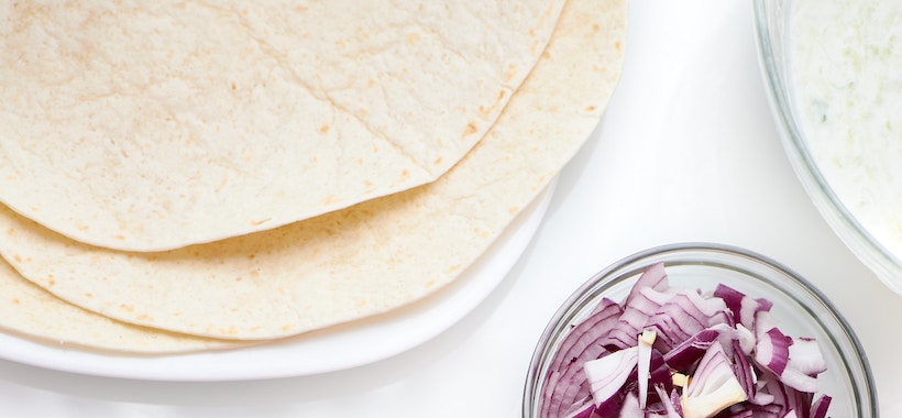 Tortillas next to a bowl of red onions