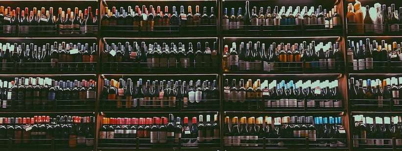 Many mostly red wines on a shelf
