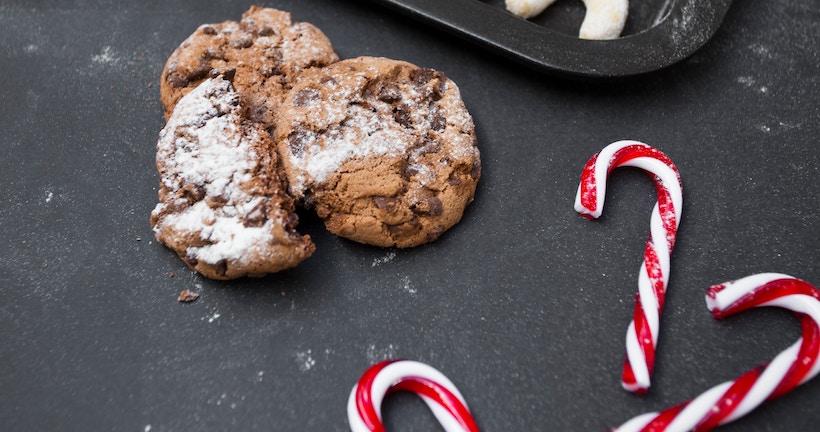 Candy canes of around 4" next to chocolate chip cookies