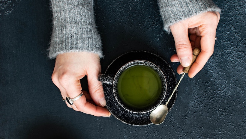Lady mixing green tea in a cup