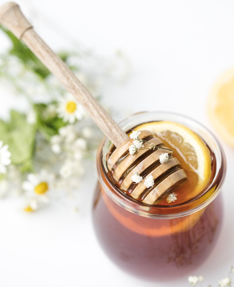 Honey and applicator inside a clear jar, with clover