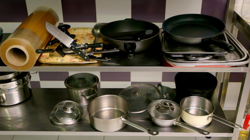 Various utensils on kitchen counter. Stainless steel pans, pots, knives at commercial kitchen. Food cooking equipment.