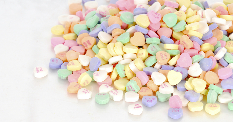 pile of candy hearts with reflection on white background