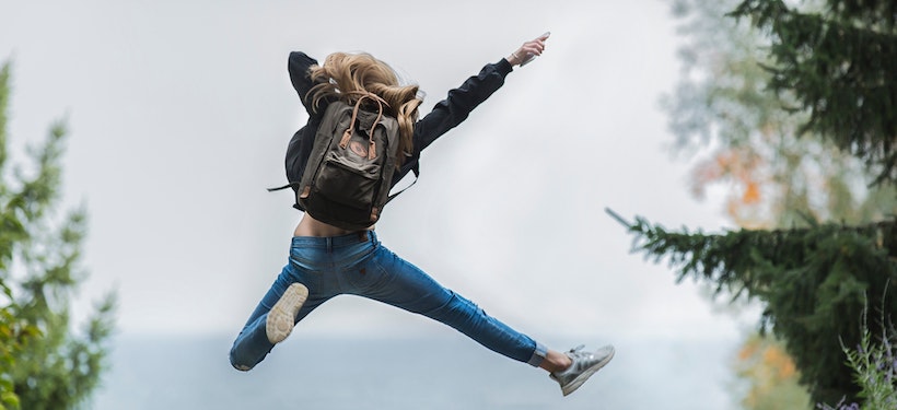 Young lady wearing a backpack jumping