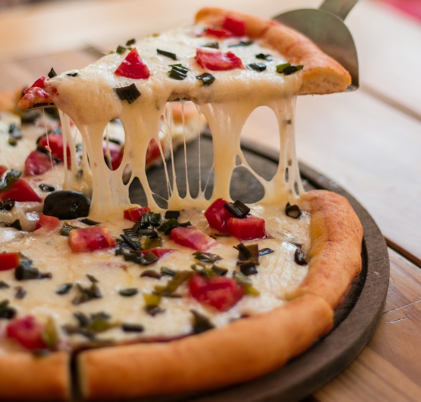 Pizza lifted showing stringy cheese connecting to pie