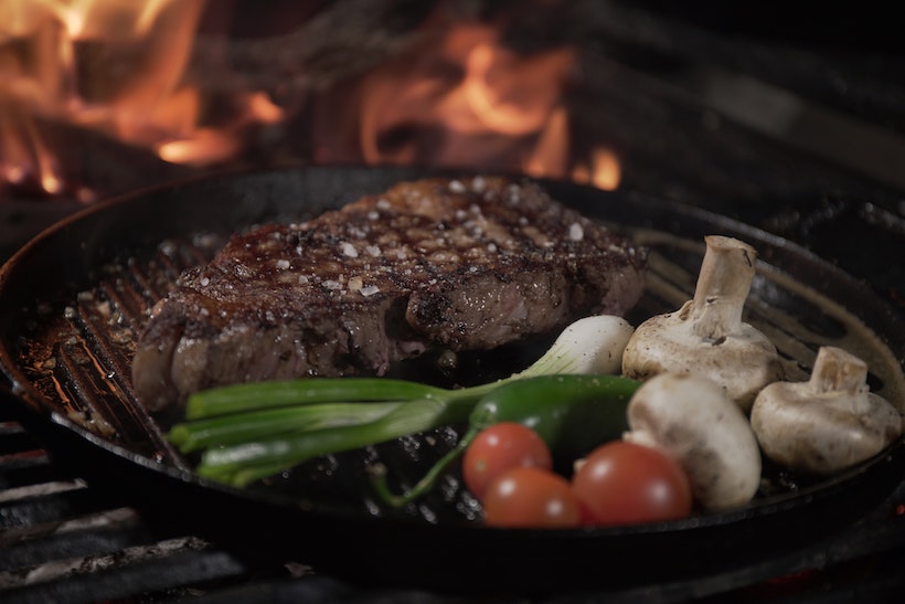 Steak, veggies, and mushrooms on a grill pan