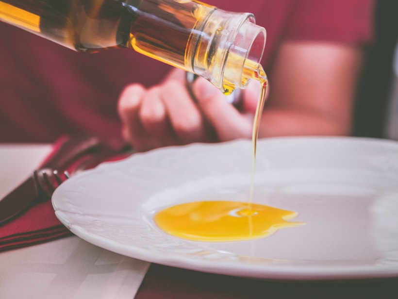 Man pouring olive oil onto a plate