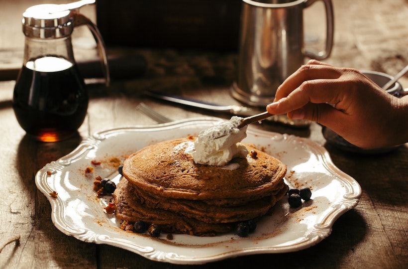 Pancake stack with butter and syrup in background