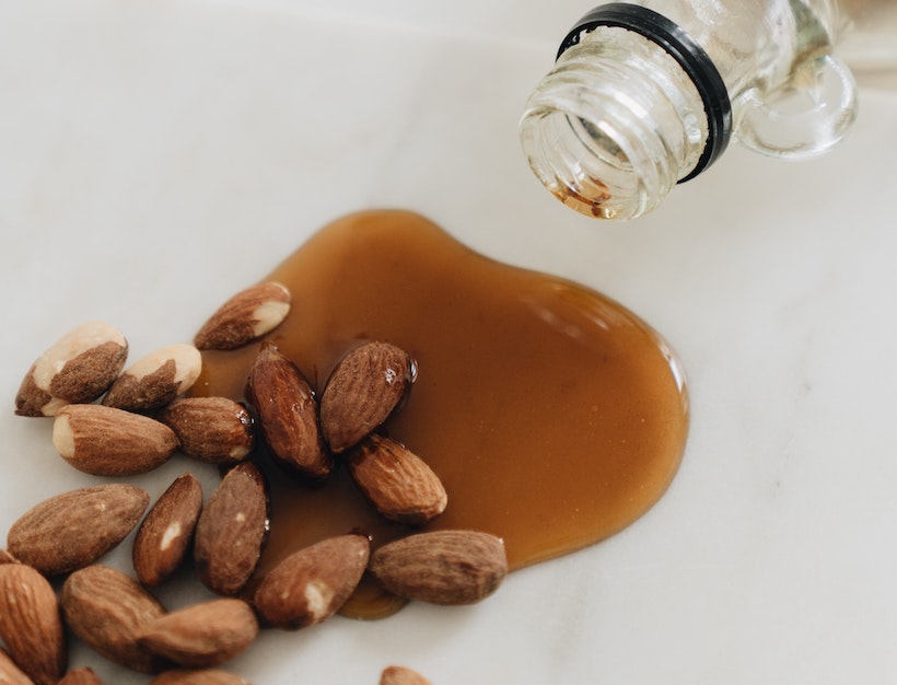 Maple syrup bottle next to almonds with syrup