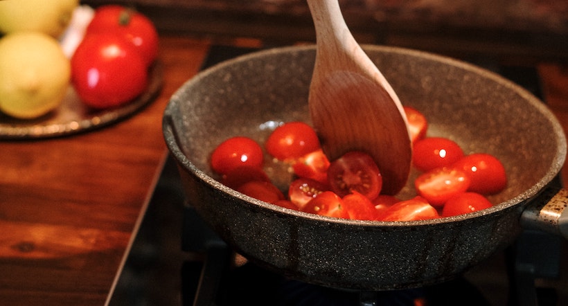 Reducing tomatoes in a pan on a burner