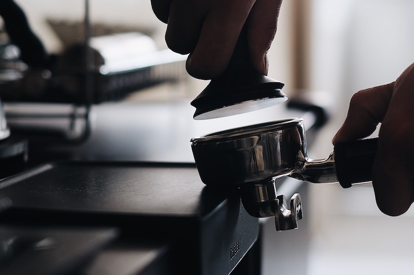 Barista about to tamp espresso in a portafilter