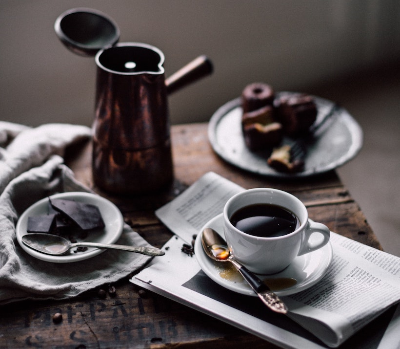 Metal carafe in background of meal with coffee and chocolate