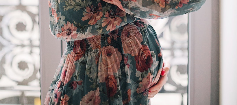 Pregnant lady holding her belly in a dress