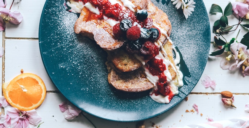 Toast with berries, cream, honey, and powdered sugar