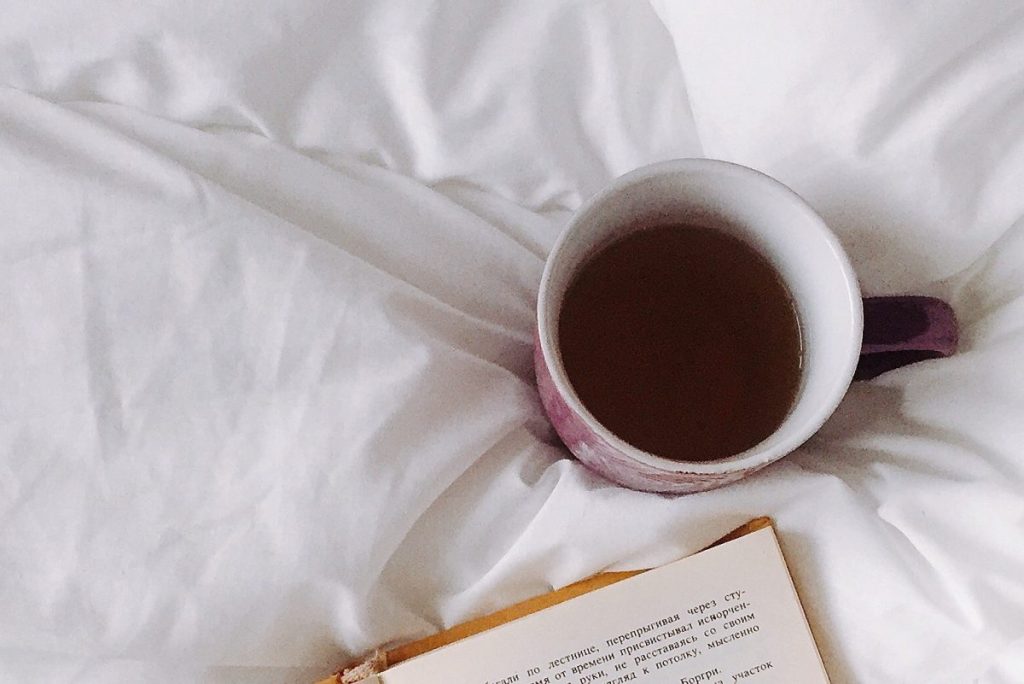 Ceramic mug of herbal tea on white sheets