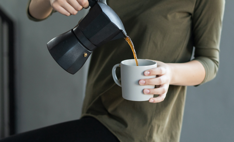 Woman in green shirt pours coffee in mug
