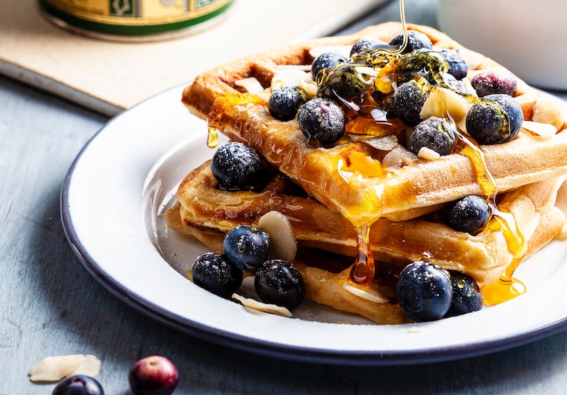 Waffles with blueberries on top and honey drizzled over