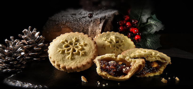 Mince pies (one split in half) in front of cake and holly