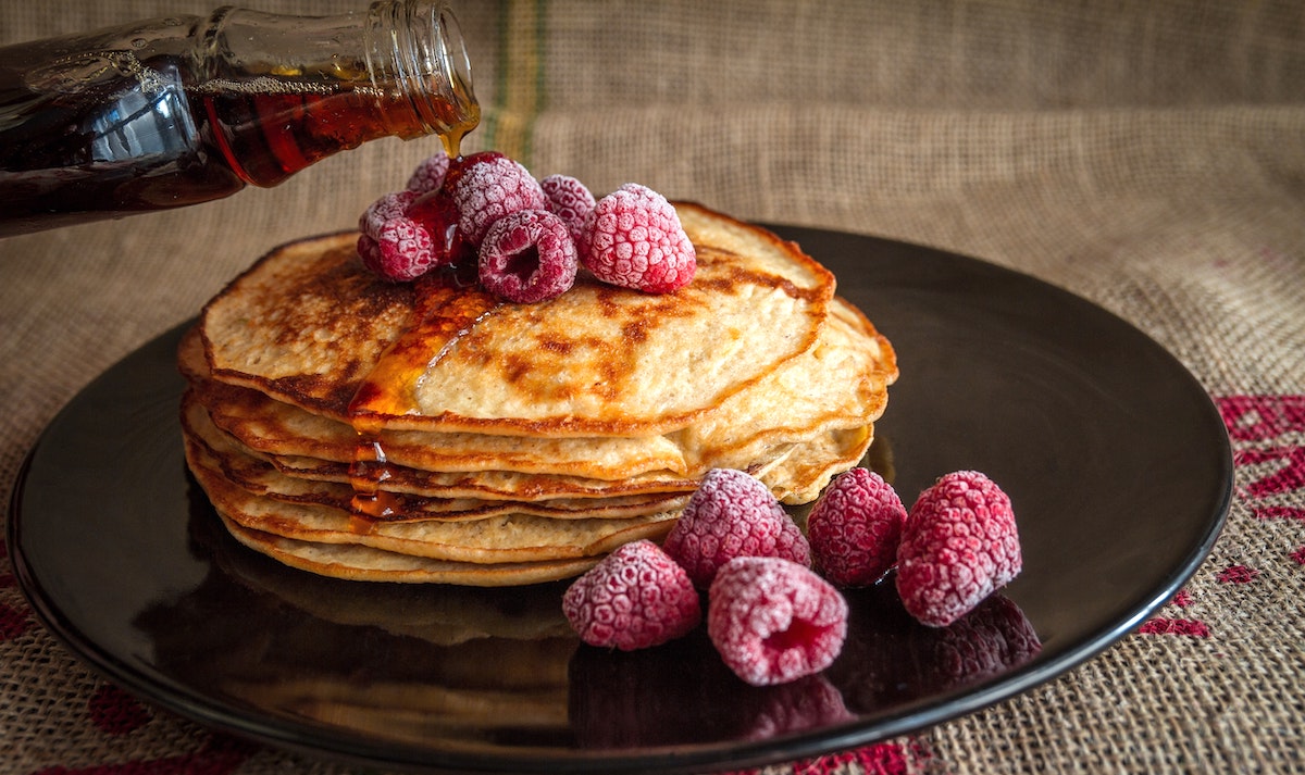 Thinner crepe style pancakes with syrup and raspberries