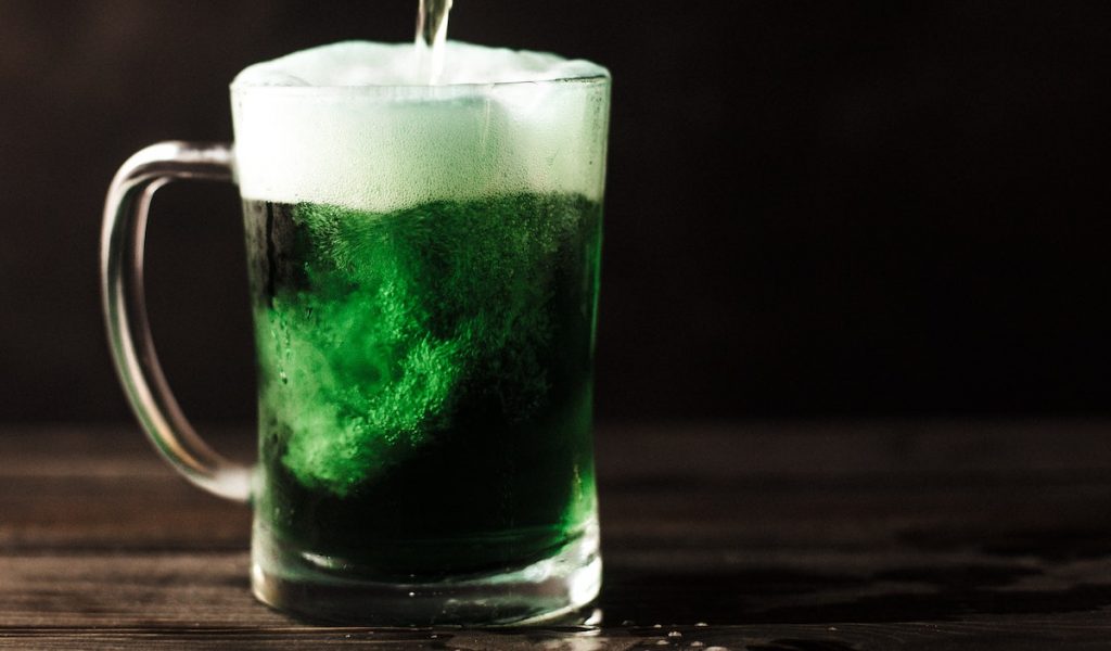 Green beer in a mug with beer being poured inside